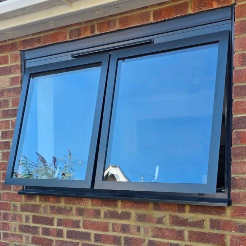 Two top hung aluminium windows. Open slightly, push out from the bottom