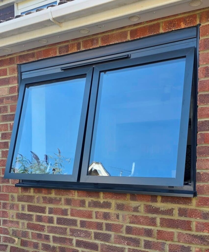 Two top hung aluminium windows. Open slightly, push out from the bottom